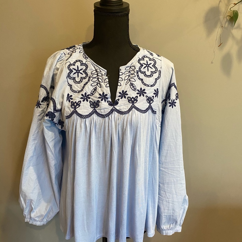 Embroidered pale blue shirt with navy stitching.